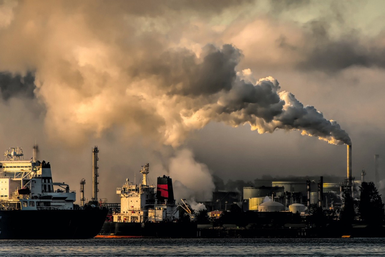 Smog billows across the sky above a shipping port.