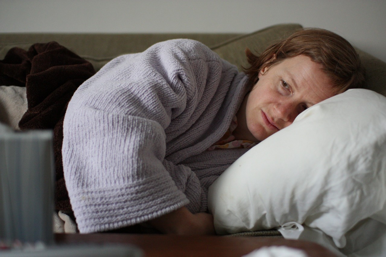 Tired, sad woman lying on a sofa.