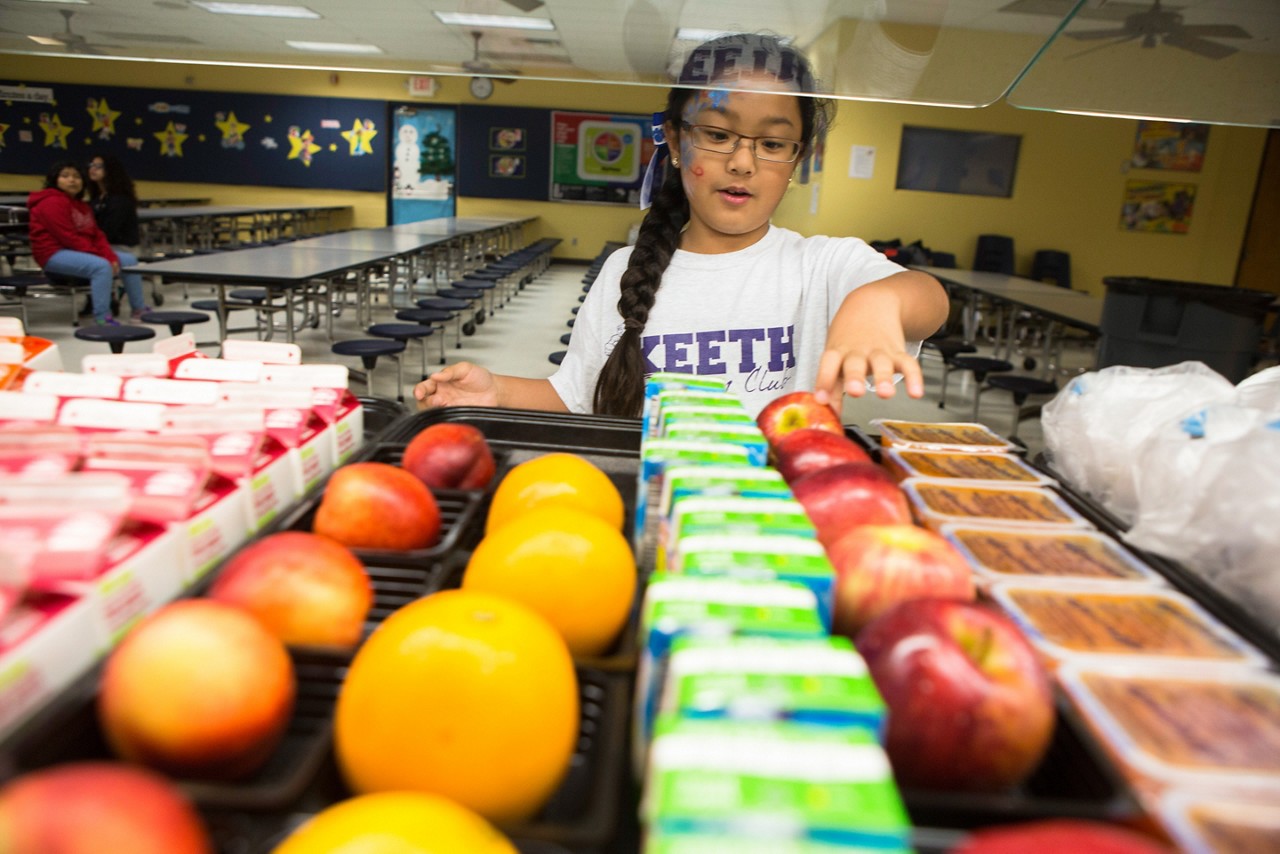 A girl selects a healthy snack in a school cafeteria. Before School Run Club, Keeth Elementary