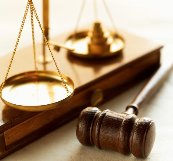 Close-up of weights balancing scales of justice with Judge's gavel beside it.