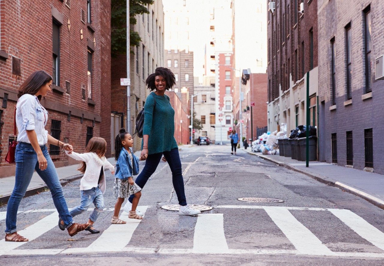Two women and their daughters crossing a street.