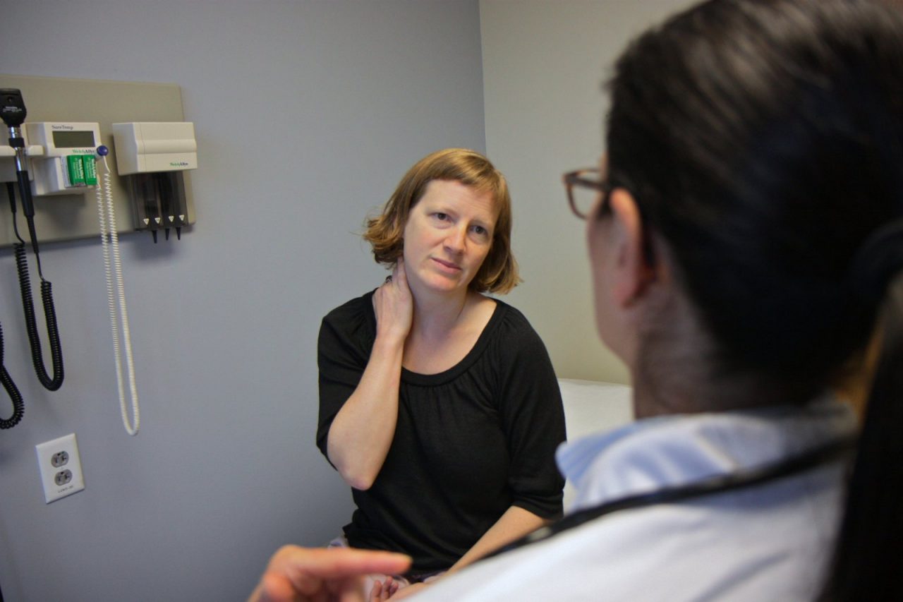 A woman talking to a doctor in an examination room.