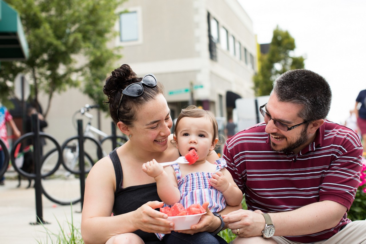 Richmond, VA COH 2017. Jana (mom), Hal (dad) and Naomi Schevitz (baby) enjoy fresh fruit at the Carytown Watermelon Festival. Each year the Shriners sell watermelons donated by Publix Super Markets with the proceeds benefiting the Shriners Hospital for children. This is the only multi-hospital pediatric system in the United States that provides care and services to children free of charge. The Shriners Hospitals for children are currently treating hundreds of children from the Richmond area.