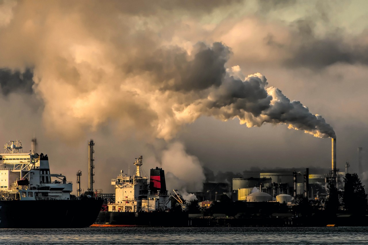 Smog billows across the sky above a shipping port.