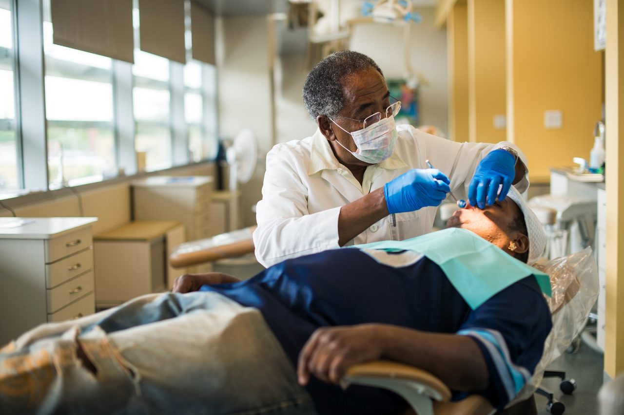 A dentist examines a patient's mouth.