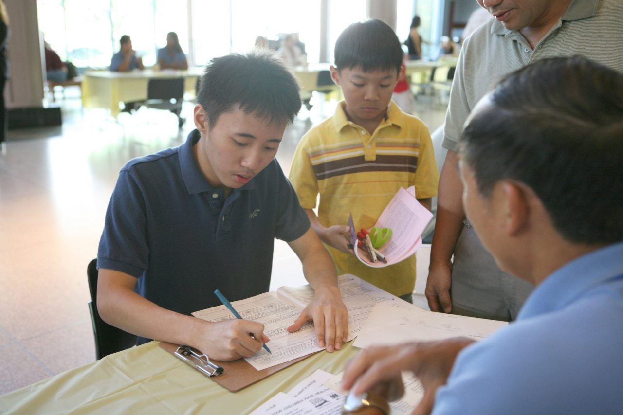 A boy fills out an application for SCHIP (State Children's Health Insurance Program) at a Covering Kids & Families enrollment event.  Covering Kids & Families