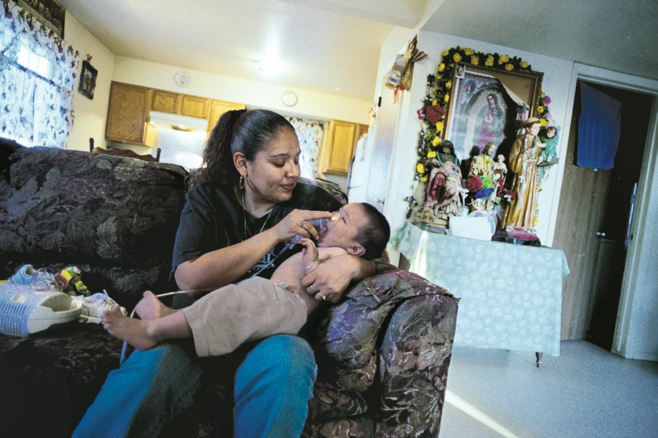 A mother gives infant a nebulizer treatment to prevent an asthma attack. 2007 Annual Report.