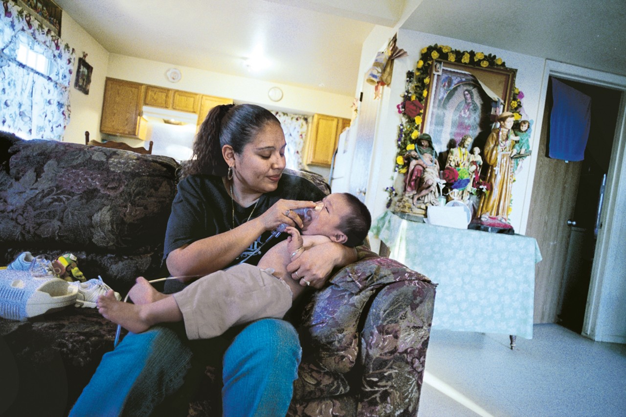 A mother gives infant a nebulizer treatment to prevent an asthma attack. 2007 Annual Report.