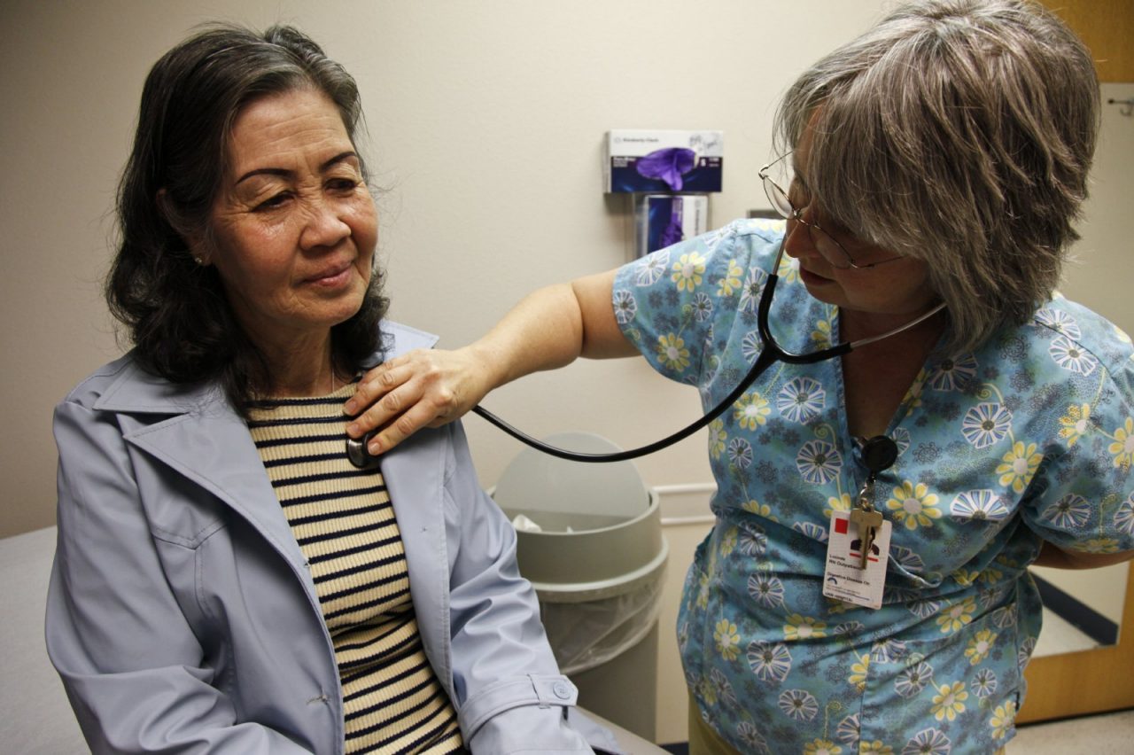 A nurse listens to a patient's chest using a stethoscope.