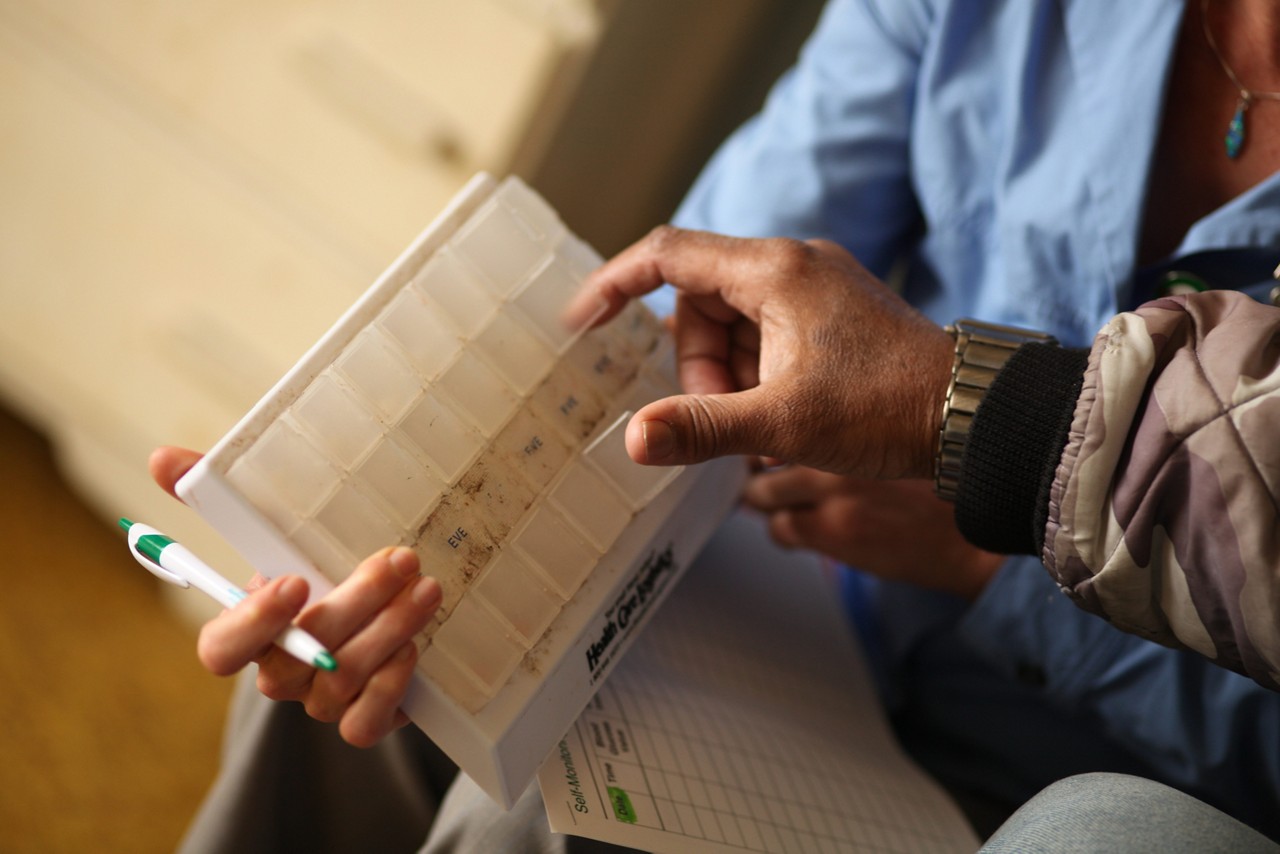 A nurse shows a patient how to use a pill box.