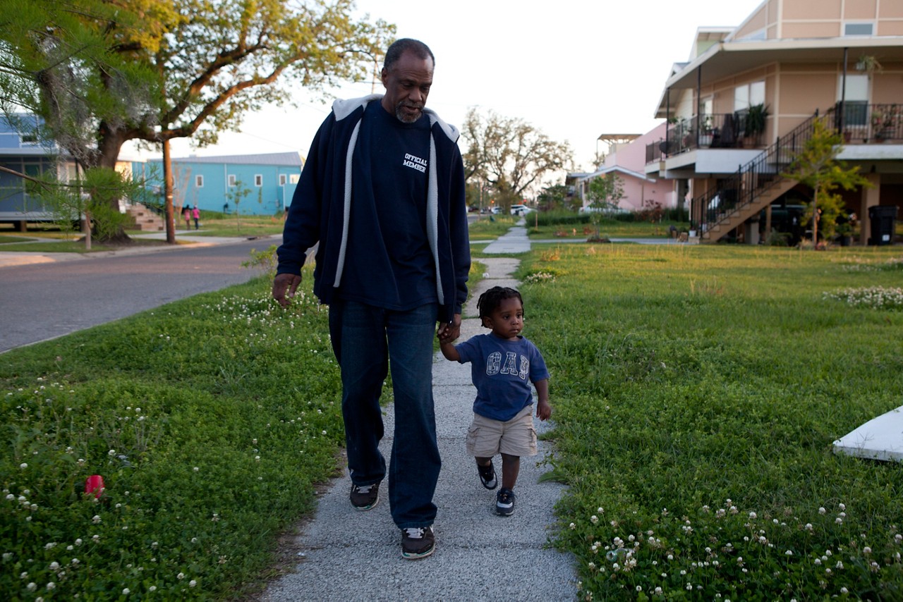 A grandfather walks through a park with his grandson.