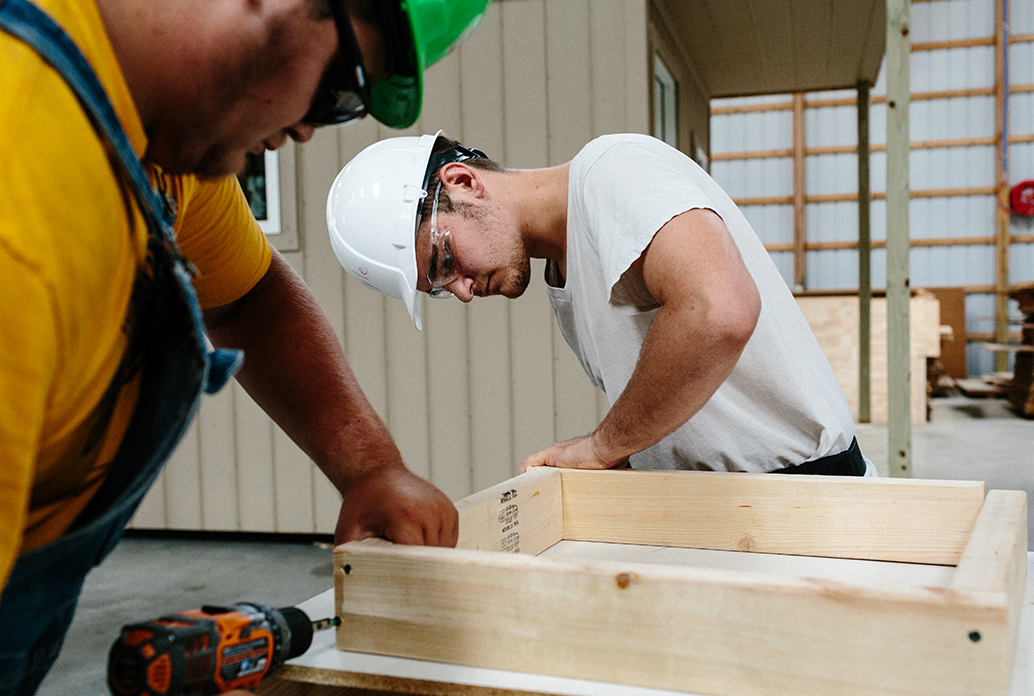 Two construction workers build a wooden frame.