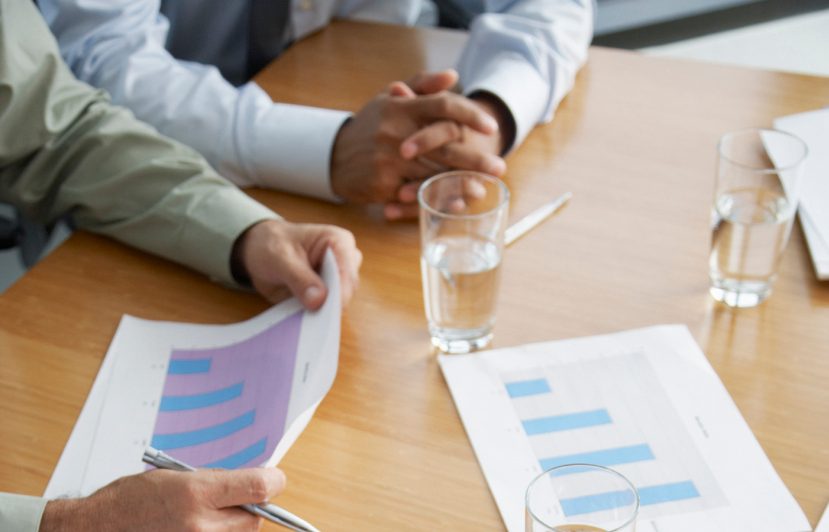 79365753 Four business people's hands at a boardroom table