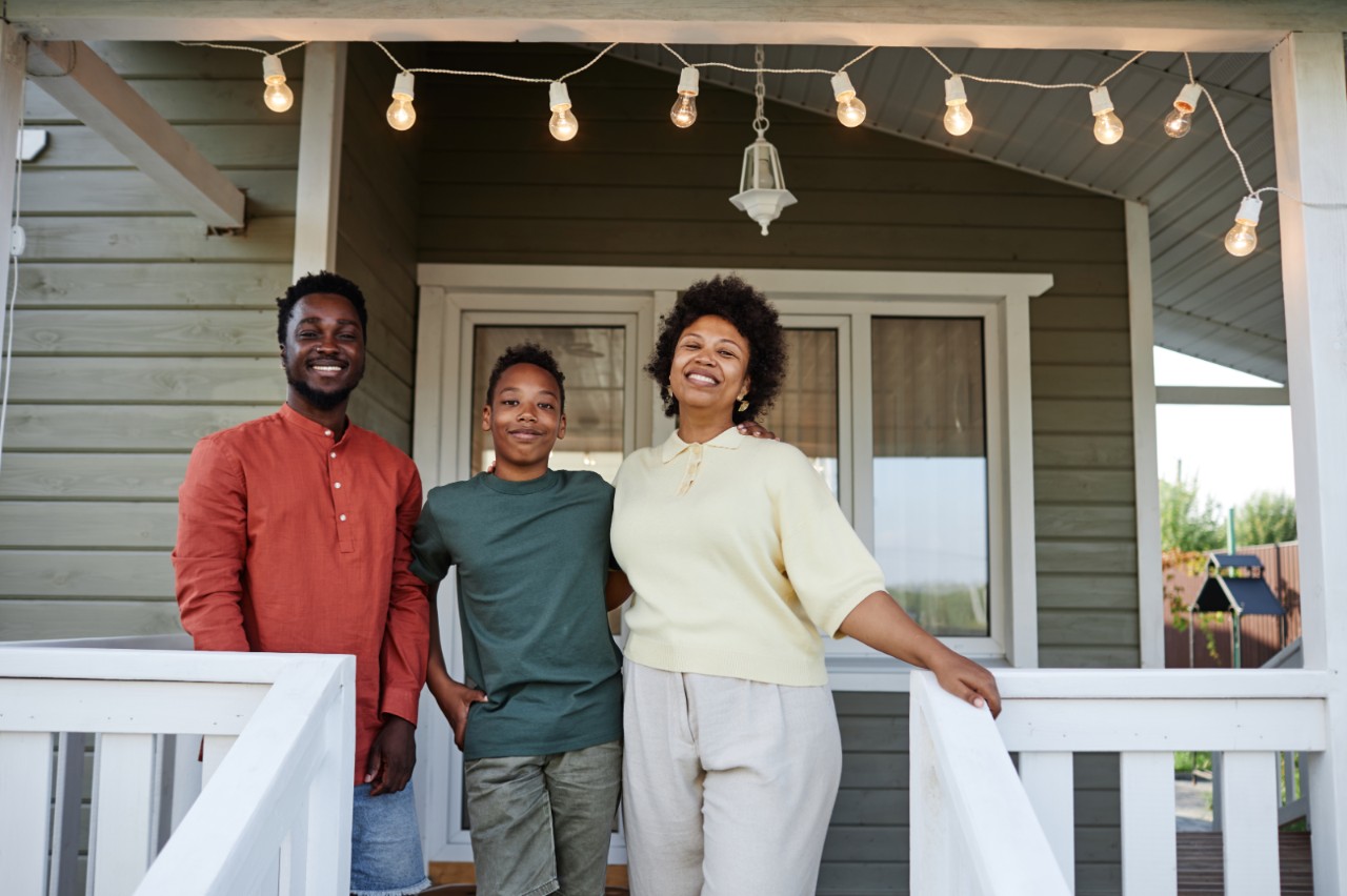 A happy family standing on the porch of their new home.