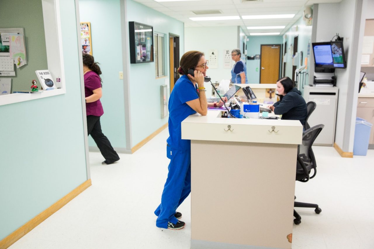 A doctor speaking on the phone at a nurses' station.