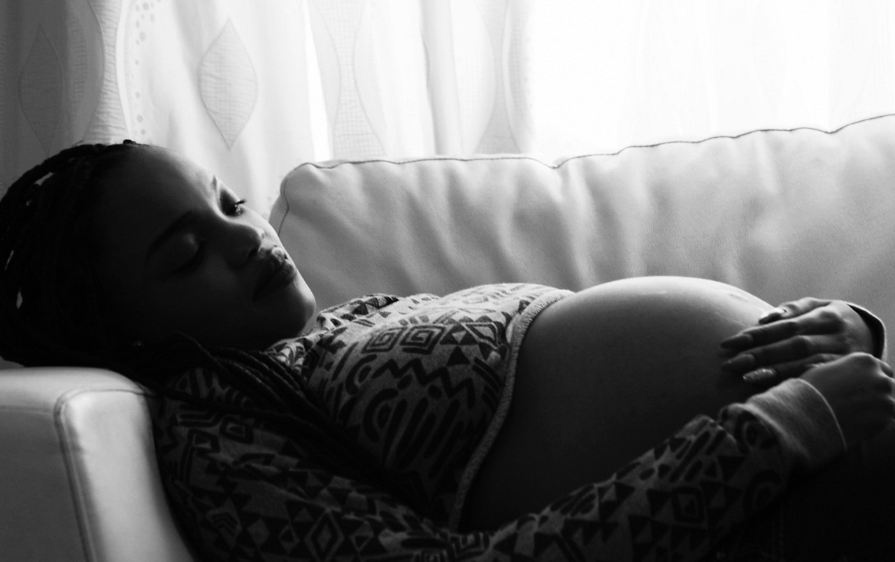 A pregnant person rests on a couch. A pregnant person rests on a couch.