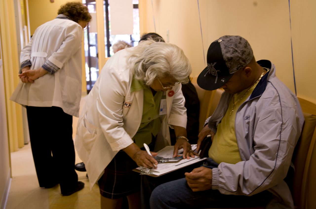 Nurses helping patients complete medical forms.