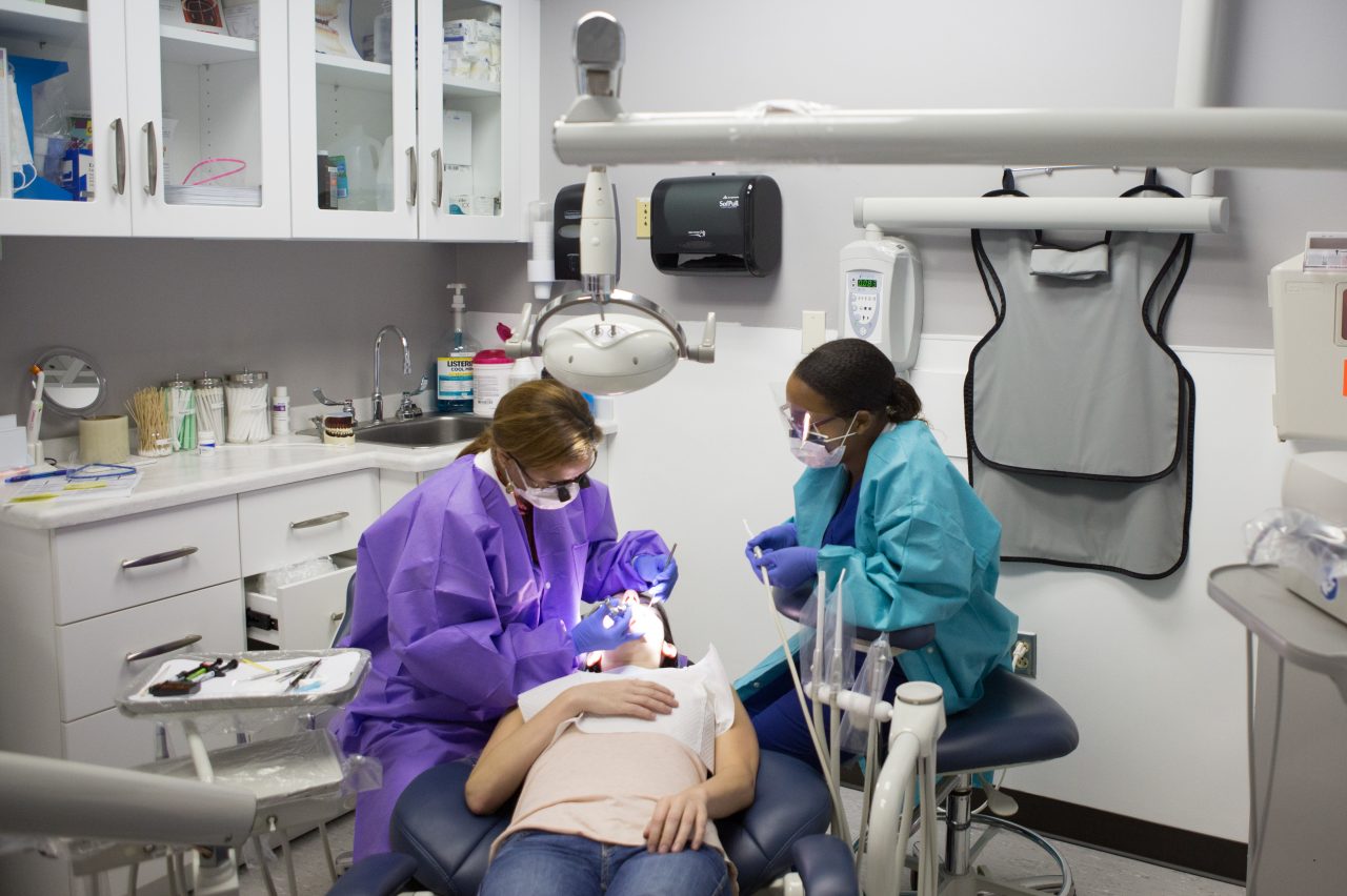 A woman gets her teeth cleaned at the dentist.