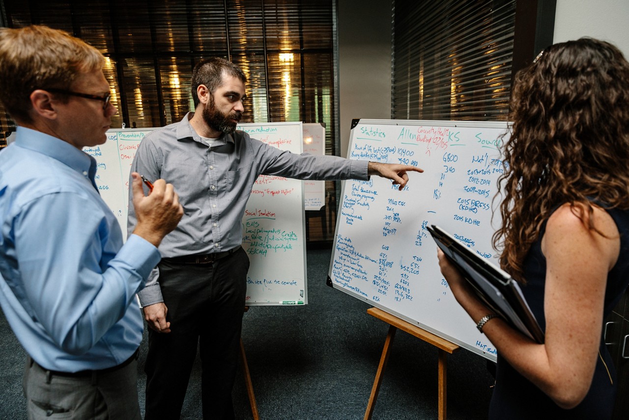 Professionals review information on a white board. 