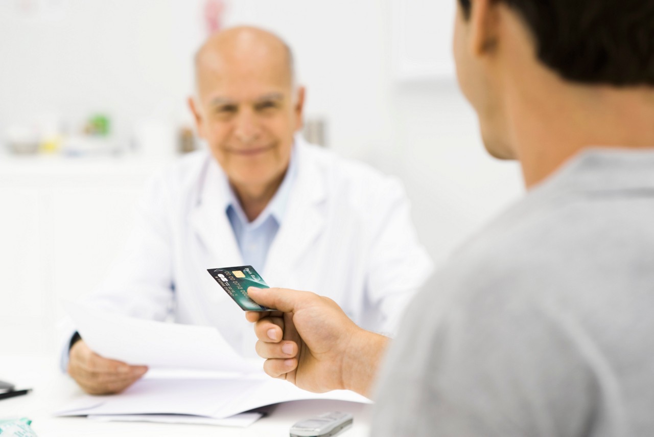 Patient handing credit card to doctor.