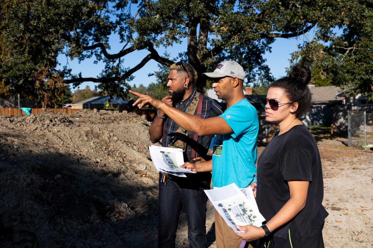 Three adults surveying and planning land to be developed.
