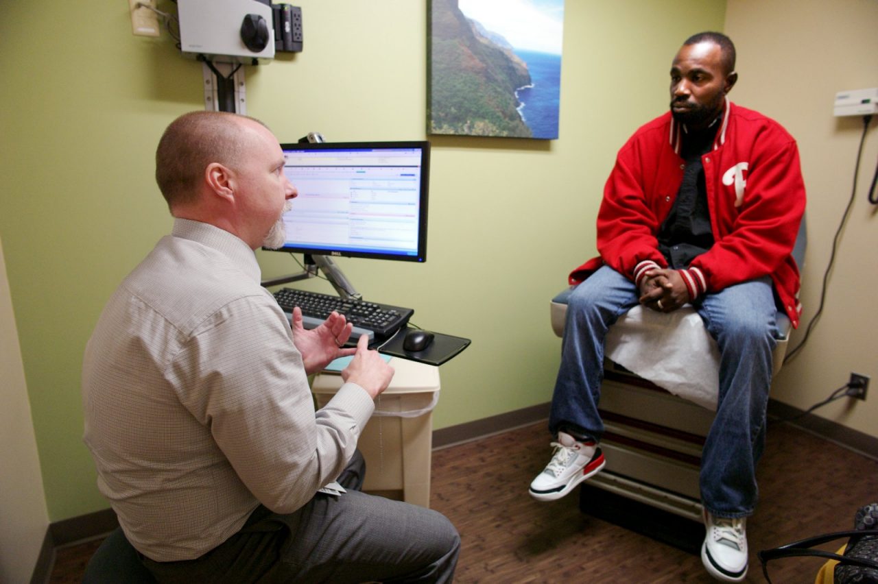 A doctor speaks with a patient in an examination room.