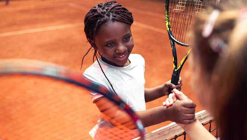 Two girls shaking hands after a tennis match.