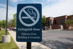 A no smoking sign outside the entrance to a parking lot.