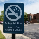 A no smoking sign outside the entrance to a parking lot. thumbnail