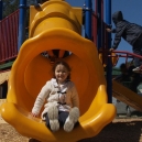 A girl pictured at the bottom of a playground slide. thumbnail