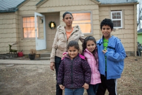 A family poses for a portrait outside of their home.