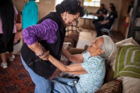 A nurse helps an elderly woman stand up.