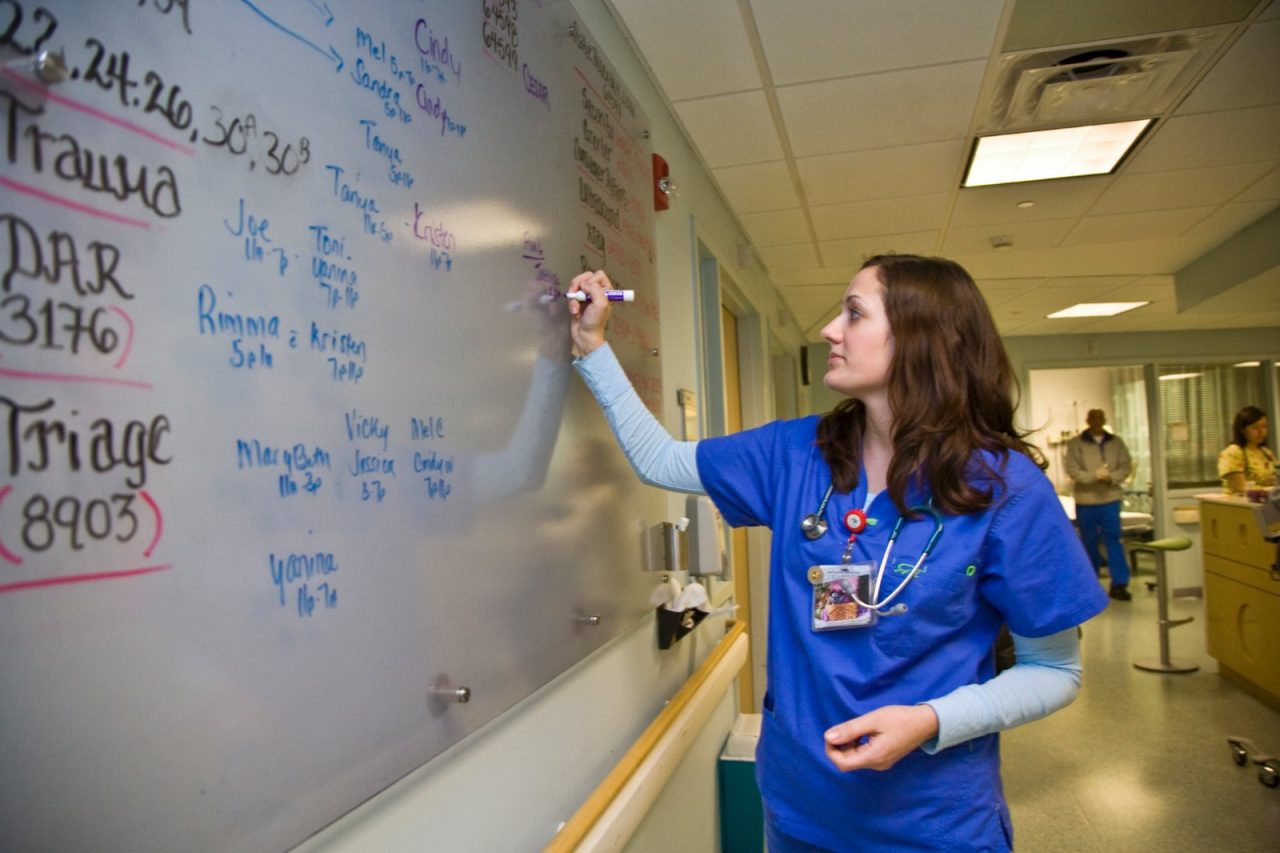 A nurse writes on the wall chart.