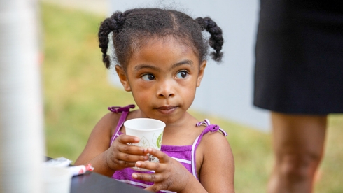 Young girl drinking from a cup.