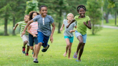 Boys and girls run and play in the park.